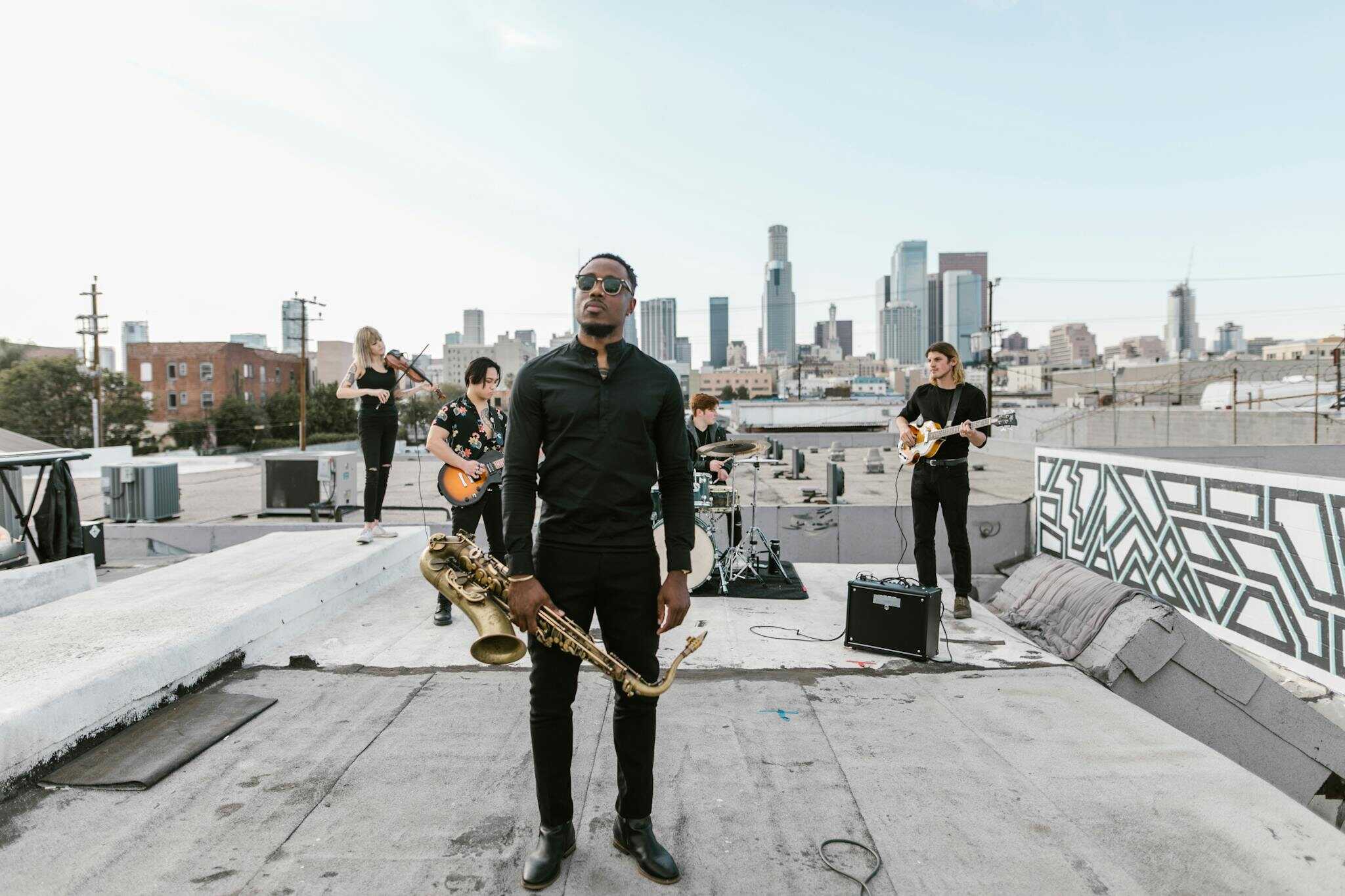 A band playing music on a rooftop with a city skyline in the background, featuring a saxophonist.